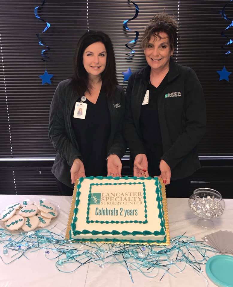 2 ladies holding a cake